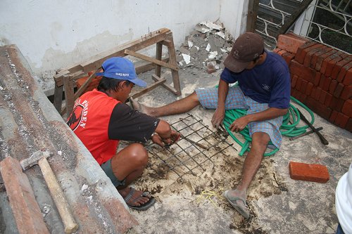 Werklieden zijn aan het werk met het vlechtijzer voor de betonnen pilaren.